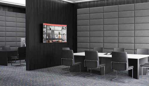 Modern conference room with black chairs, a large table, Vant Panels on the wall, and a screen.